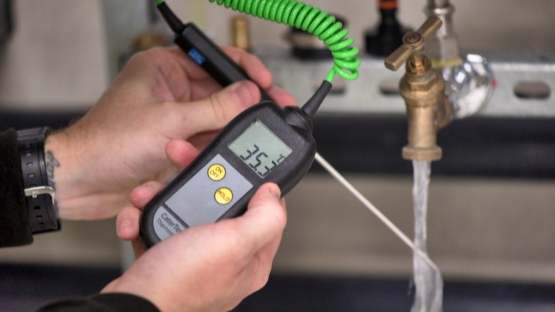 Hand-held meter testing water at a tap