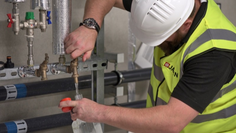 Engineer sampling water from a building's pipework