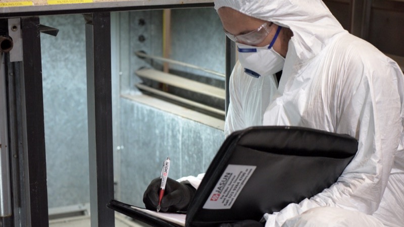Technician in protective equipment inspecting an LEV system